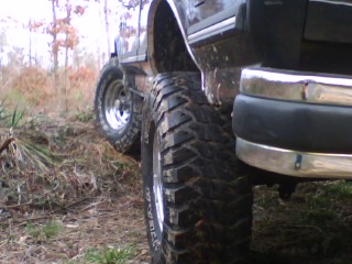1990 Ford Bronco - A vehicle with large tires is shown from the side, parked on uneven terrain.