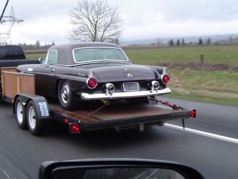 1989 Ford Bronco - A classic Ford Thunderbird is transported on a trailer down a highway.