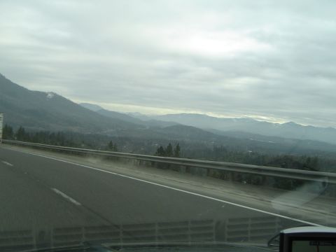 1989 Ford Bronco - A view from a vehicle traveling on a highway, with mountains in the distance under a cloudy sky.