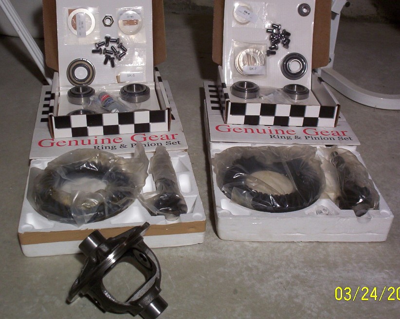 Two Genuine Gear ring and pinion sets with install kits and a differential carrier on a concrete floor