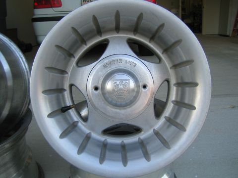 1995 Ford Bronco - Face-on shot of a bare polished aluminum Center Line wheel standing on a garage floor, showing the CENTER LINE lettering around the recesse…