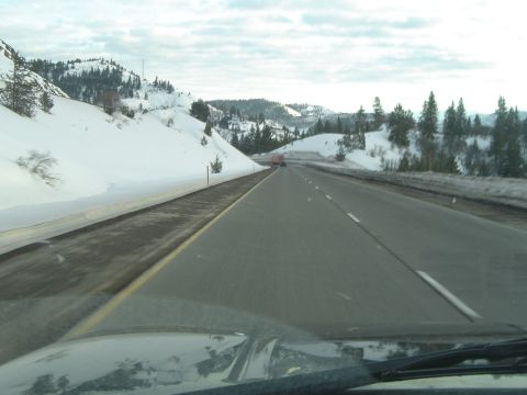 1989 Ford Bronco - Driving on a highway surrounded by snow-covered hills and evergreen trees.