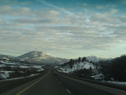 1989 Ford Bronco - A view from a vehicle traveling on a highway through a mountainous area with snow on the ground and scattered trees.