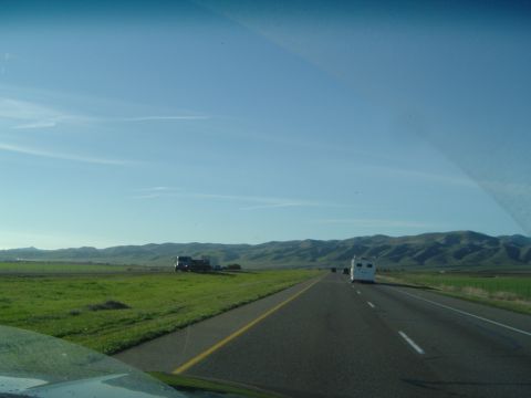 1989 Ford Bronco - A truck and RV travel down a highway with green fields and rolling hills under a clear blue sky.