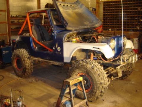 1992 Ford Bronco - This modified Jeep CJ is undergoing work in a garage, with its hood open revealing the engine compartment.
