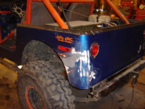 1992 Ford Bronco - This blue off-road vehicle has an orange roll cage and visible damage to its rear quarter panel.