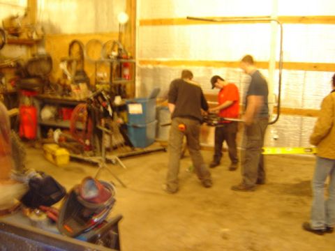 1992 Ford Bronco - Several individuals are engaged in work within a workshop, surrounded by various tools and storage units.