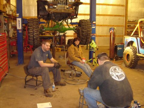 1992 Ford Bronco - People gather in a workshop around a vehicle undergoing extensive modifications and repairs.