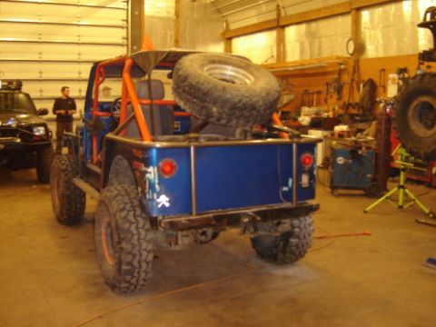 1992 Ford Bronco - Modified blue jeep in a garage setting with a black SUV in the background.
