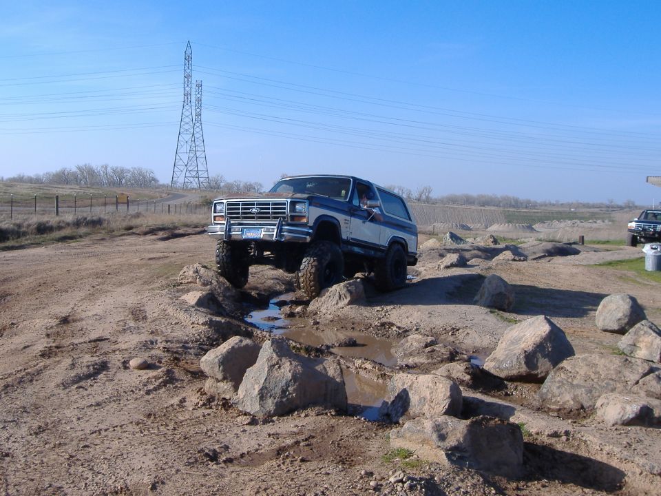 Blue and white 1986 Ford Bronco navigating rocky terrain