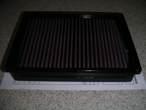 2002 BMW M3 - A black air filter with red filter media is shown, resting on a document.