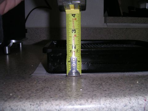 2002 BMW M3 - A tape measure is used to measure the height of a black automotive part, indicating it is approximately 3 inches tall.