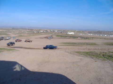 1986 Ford Bronco - Multiple vehicles navigate a dusty off-road course under a clear blue sky.