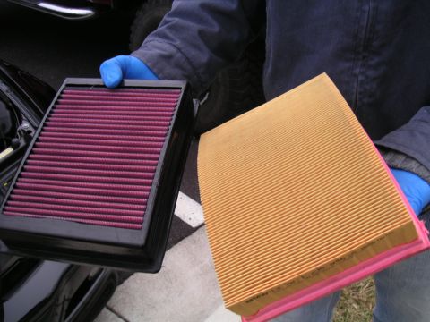 2002 BMW M3 - A person in blue gloves holds up a clean purple air filter next to a used orange air filter.