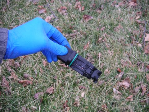 2002 BMW M3 - A mass air flow sensor is held by a gloved hand against a grassy background.
