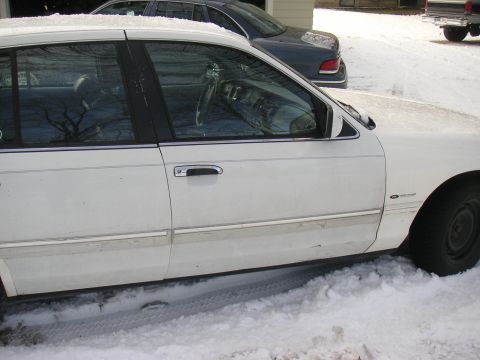 1997 Ford Crown Victoria - Side view of a white 1997 Ford Crown Victoria parked in the snow, showing the door and interior.