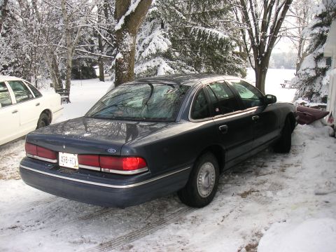 1997 Ford Crown Victoria - A dark blue sedan sits in the snow, with a white sedan parked nearby.