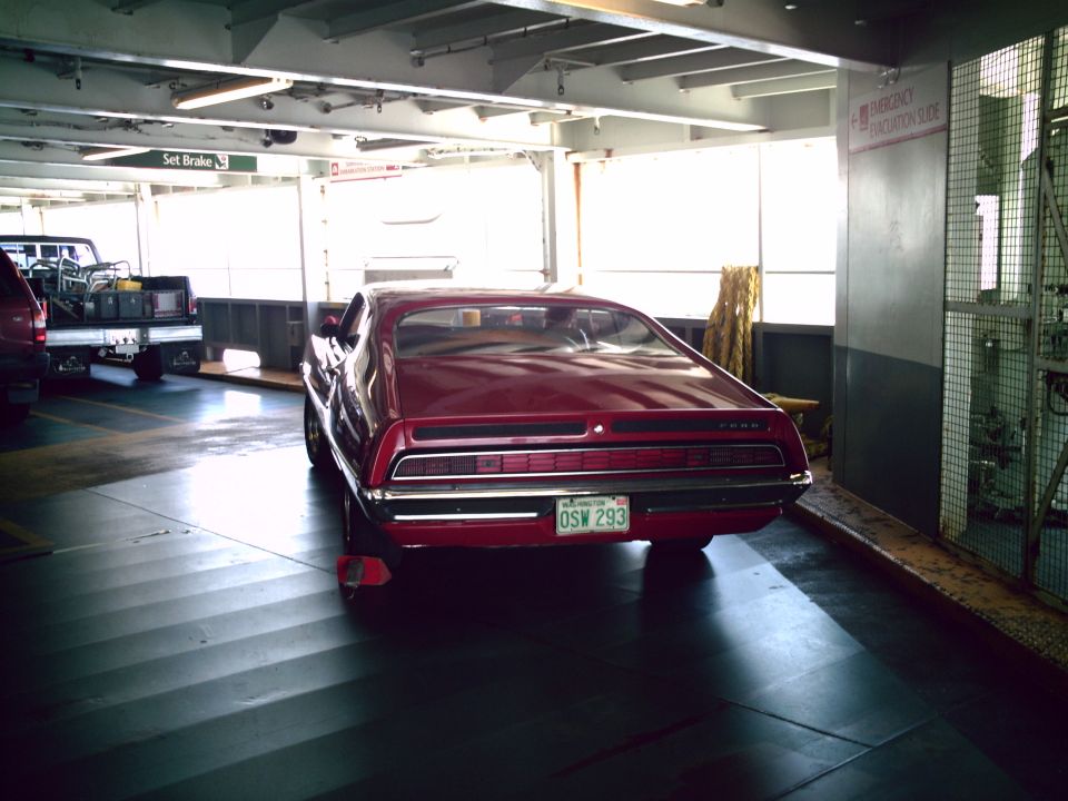 Rear of red Ford Torino fastback with Washington plate OSW 293 parked on a ferry car deck