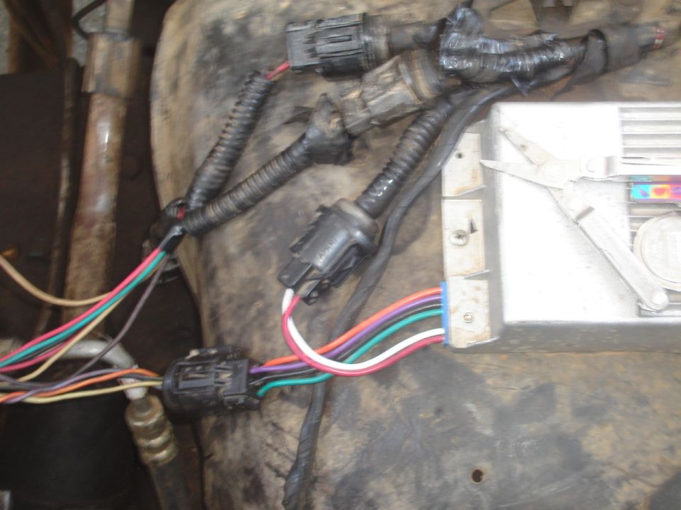 Wiring harness connectors and colored wires next to a finned aluminum ECM module