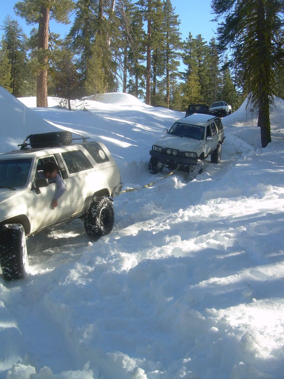 1993 Toyota 4Runner and other SUVs driving in deep snow on a wooded trail