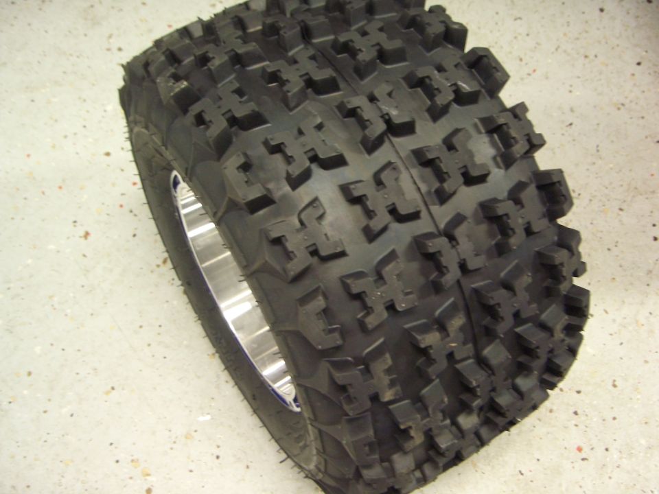 New blocky-lug off-road tire mounted on a polished aluminum wheel lying on concrete