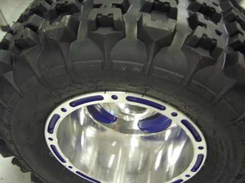 1974 Ford Bronco - A tire with the marking AT20 X 11-9 is mounted on a shiny custom wheel with blue accents.
