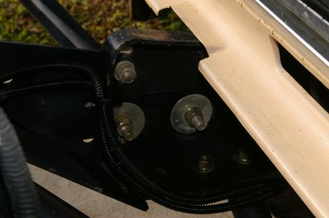1986 Ford Bronco - Close-up view of vehicle frame components, including clevis mounts and wiring, with beige trim.
