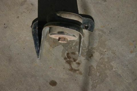 1991 Ford Bronco - A close-up view of a suspension component, likely from a vehicle's undercarriage, resting on a concrete surface.