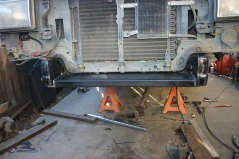 1991 Ford Bronco - The front end of a Ford Bronco is elevated on jack stands, revealing its grille and headlights.
