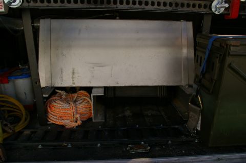1986 Ford Bronco - Cargo area storage setup with a large tank and coiled rope.
