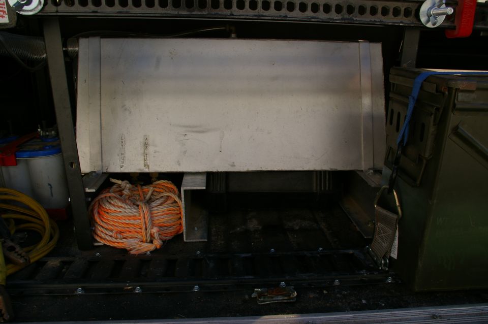 Interior view of vehicle cargo area showing a large aluminum tank, coiled rope, and storage containers