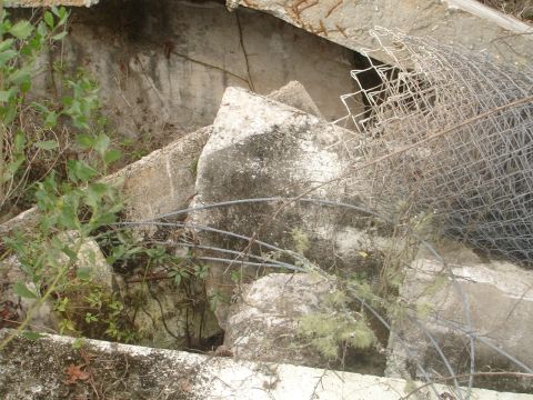 1989 Ford Bronco - Debris from construction or demolition, including concrete and fencing, with vegetation growing around it.