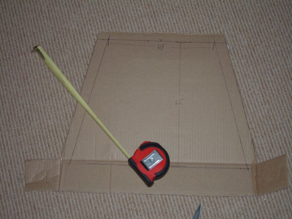 Cardboard mockup template marked 10 inches by 12 inches with a red tape measure extended across it