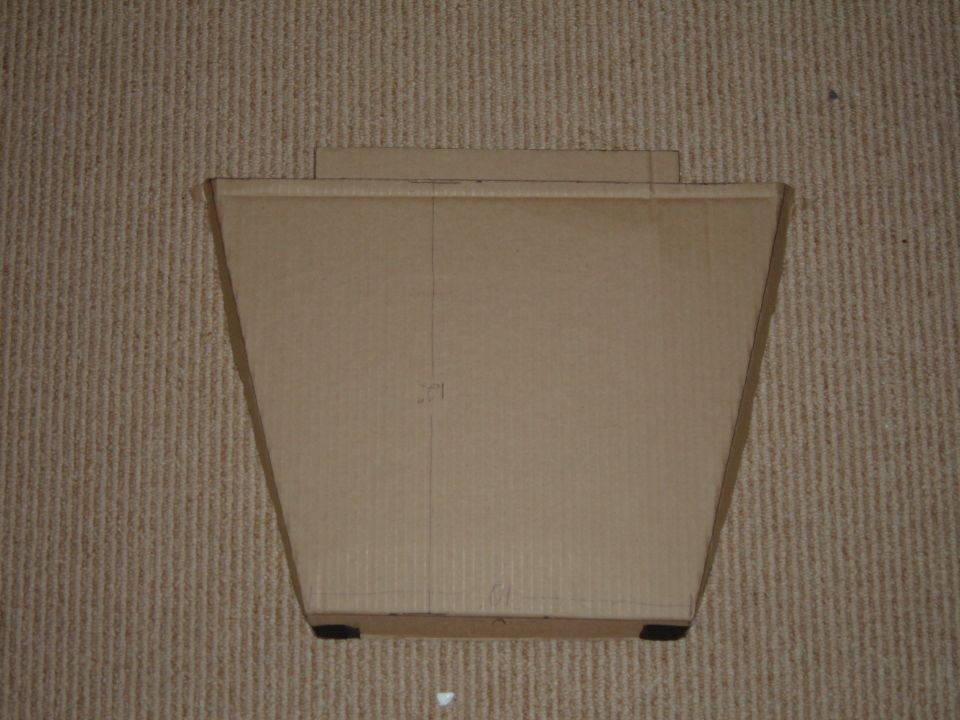 Trapezoidal cardboard rack template with pencil marks laid on beige carpet
