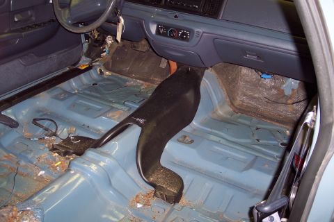 2001 Ford Crown Victoria - The interior of a car has been stripped down, revealing the bare floor and dashboard components.