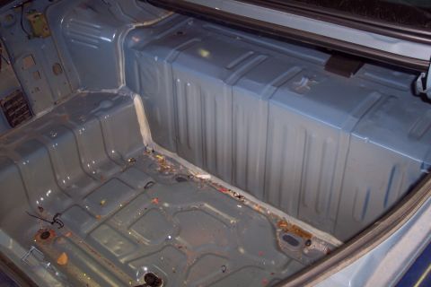 2001 Ford Crown Victoria - The interior of a car trunk is shown, stripped bare and showing signs of wear and tear.