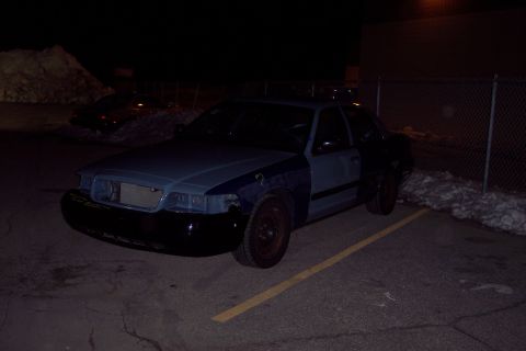 2001 Ford Crown Victoria - This 2001 Ford Crown Victoria is parked at night with its front end showing signs of repair or disassembly.