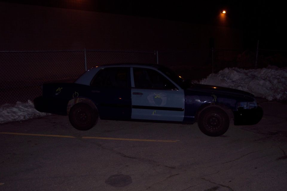 Side view of a dark blue and light blue Ford Crown Victoria with mismatched doors and steel wheels
