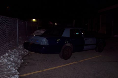 2001 Ford Crown Victoria - A dark blue and grey 2001 Ford Crown Victoria is parked outdoors at night, viewed from the rear quarter angle.