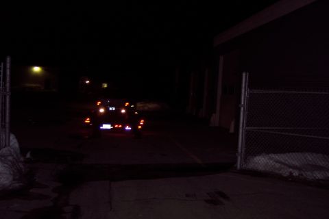 2001 Ford Crown Victoria - A dark vehicle is seen from the rear at night, its brake lights glowing in the darkness.