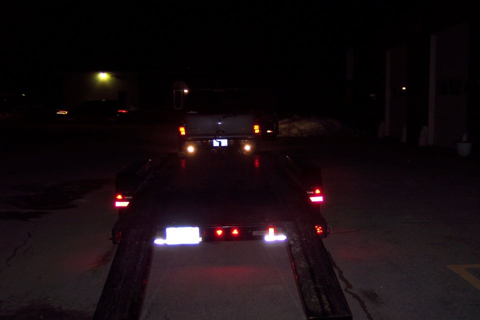 Rear view of a trailer at night with a vehicle on it