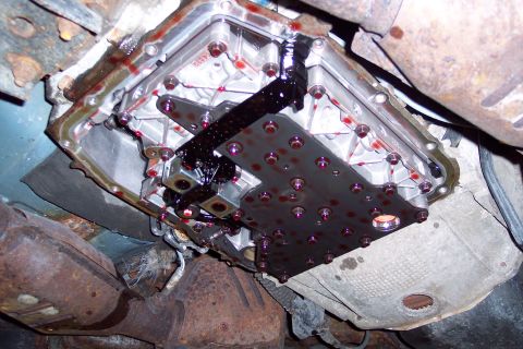 2001 Ford Crown Victoria - Underside view of a vehicle's transmission pan, revealing internal components and fluid residue.