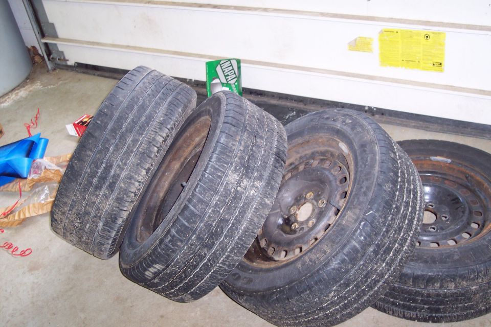 four used tires on steel rims, one with rust