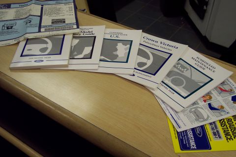 2001 Ford Crown Victoria - A collection of Ford Crown Victoria owner's manuals and a roadside assistance guide are laid out on a wooden surface.