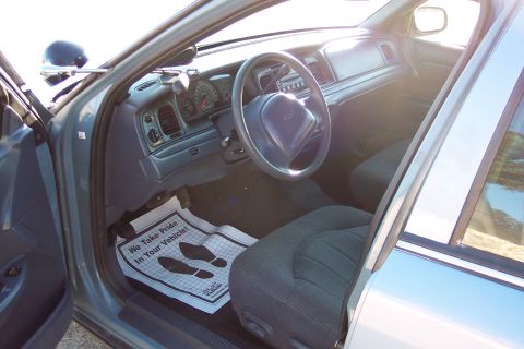 2001 Ford Crown Victoria - The interior of a 2001 Ford Crown Victoria, the dashboard, steering wheel, and a floor mat with a 'We Take Pride In Your Vehicle!' message.