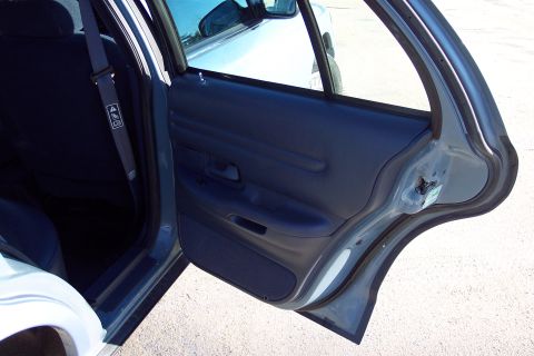 2001 Ford Crown Victoria - Close-up view of the interior door panel and seatbelt of a car.
