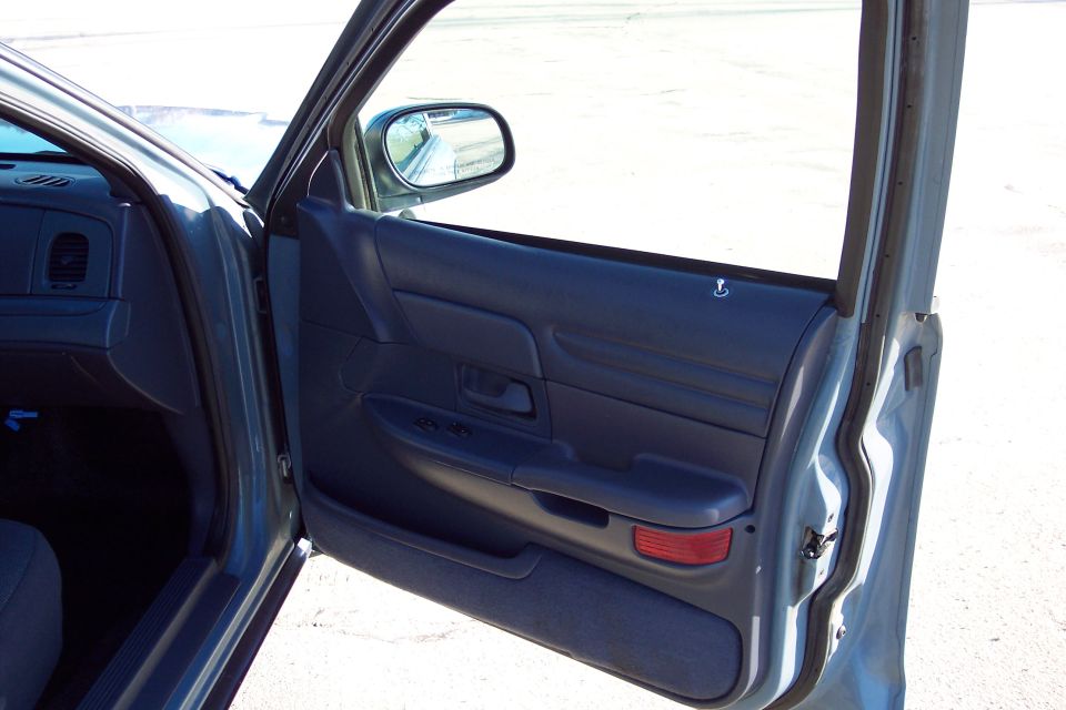 Blue interior door panel of a 2001 Ford Crown Victoria, showing the armrest, window controls, and side mirror