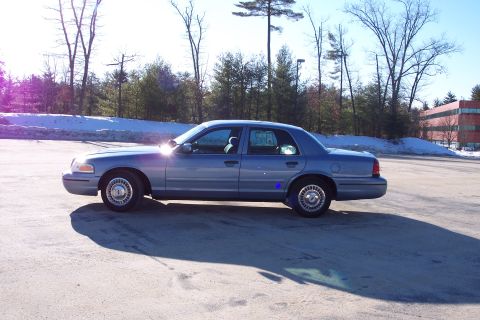 2001 Ford Crown Victoria - Side profile of a blue 2001 Ford Crown Victoria sedan parked outdoors on a sunny day.