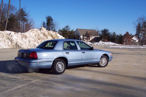 2001 Ford Crown Victoria - A light blue 2001 Ford Crown Victoria sedan is viewed from the rear quarter angle on a sunny day with snow in the background.