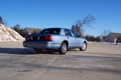 2001 Ford Crown Victoria - Rear view of a light blue 2001 Ford Crown Victoria sedan parked outdoors on a clear day.